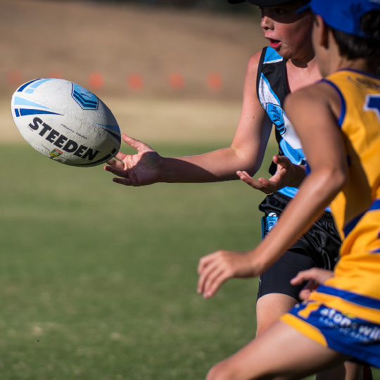 Player in blue with hands out about to catch a football while another player in yellow moves to intercept